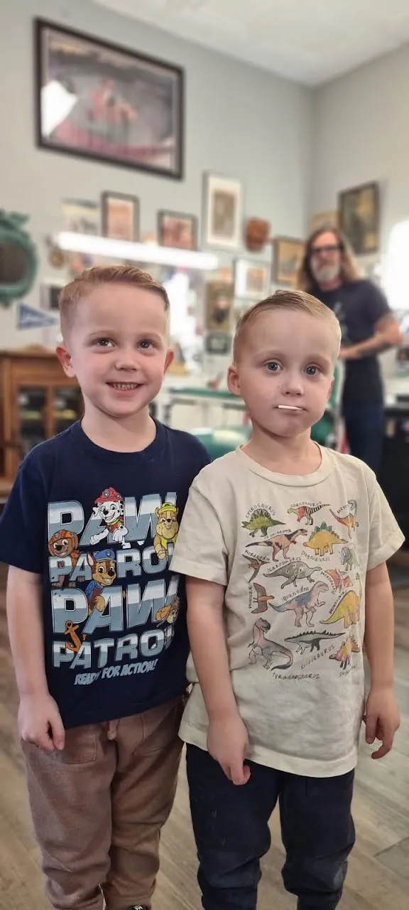 Two boys showing off new haircuts by Jill at the barbershop, wearing Paw Patrol and dinosaur t-shirts