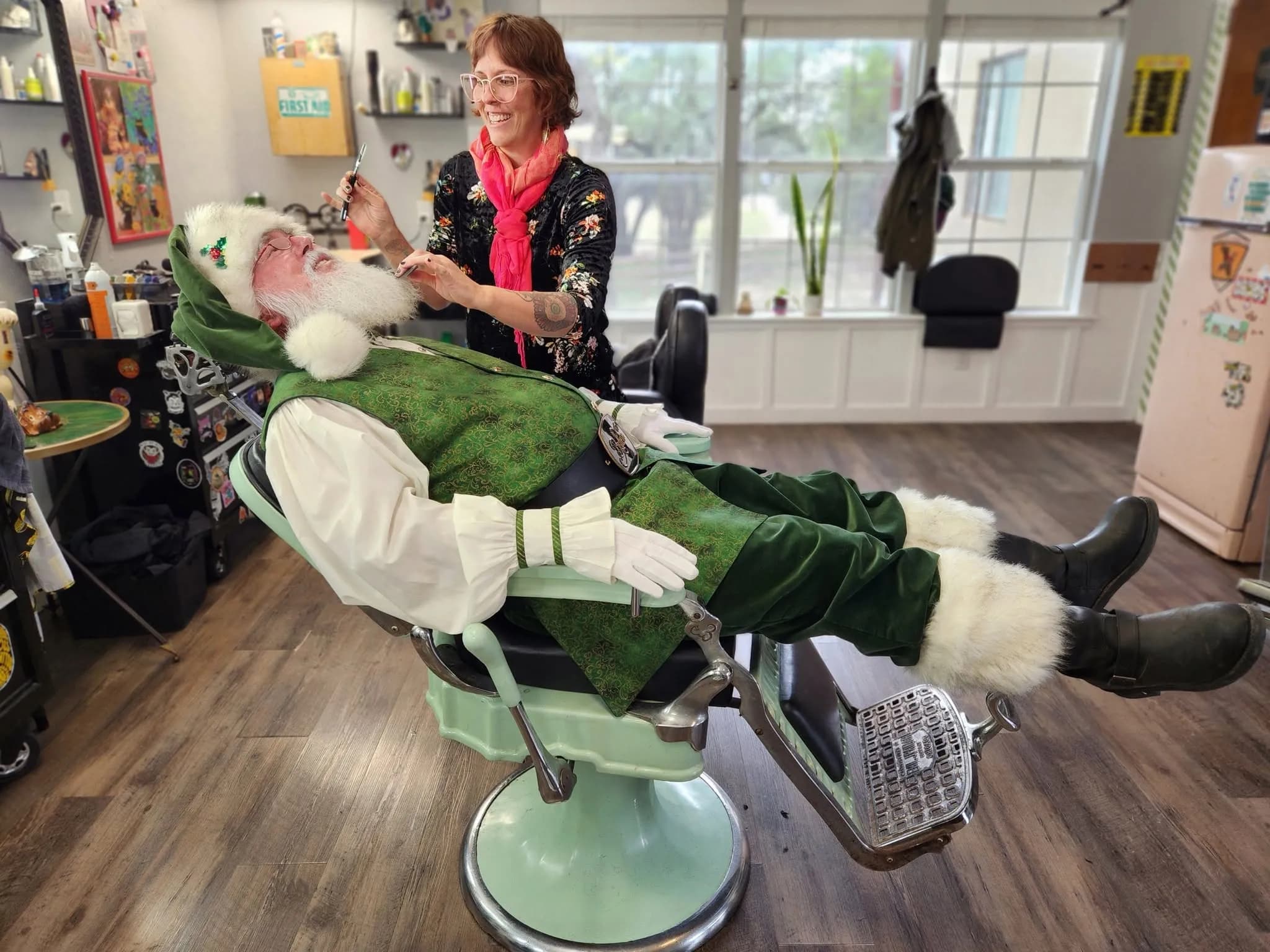 Jill trimming Santa's beard in a vintage barber chair at the barbershop